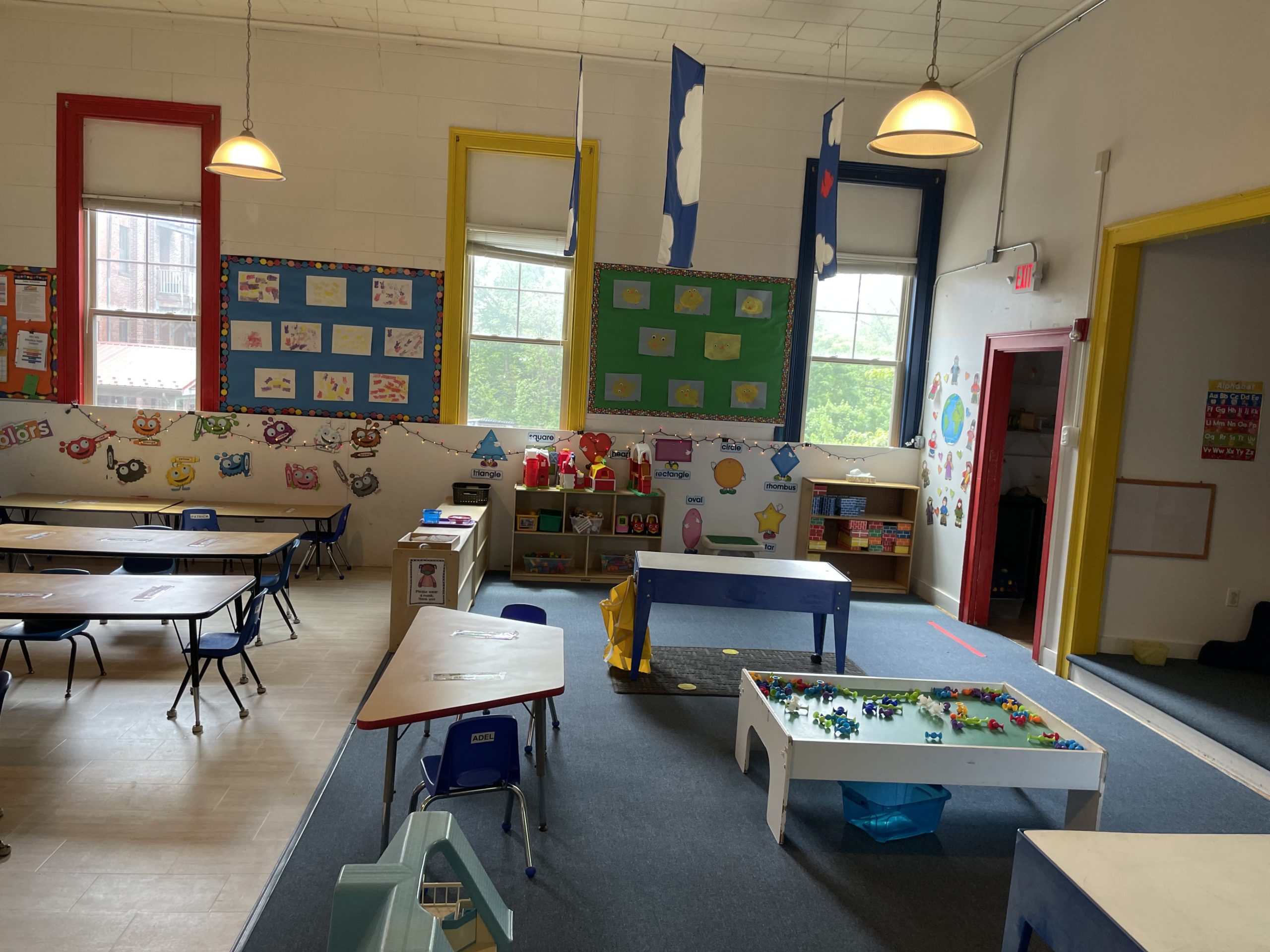 preschool classroom with desks and activities featuring colorful student artwork on walls